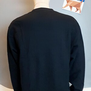 Puede incluir: Una camisa negra de manga larga en un maniqu&iacute;. La camisa tiene cuello redondo y est&aacute; hecha de una tela suave y c&oacute;moda.
