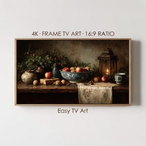 May include: A framed digital artwork for a TV screen, featuring a still life with a rustic aesthetic. The scene includes a bowl of apples, walnuts, a lit lantern, and a floral-patterned tablecloth. Text on the frame reads "4K FRAME TV ART 16:9 RATIO" and "Easy TV Art."