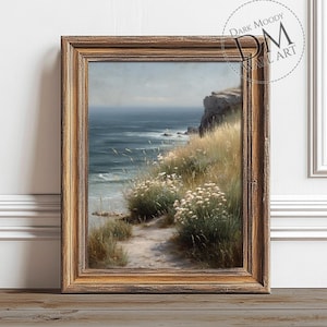 May include: A framed landscape print featuring a coastal scene. The artwork depicts a path leading to the ocean, with cliffs, tall grass, and white flowers. The frame is a warm, golden brown color. The text "DARK MOODY WALL ART" is visible.