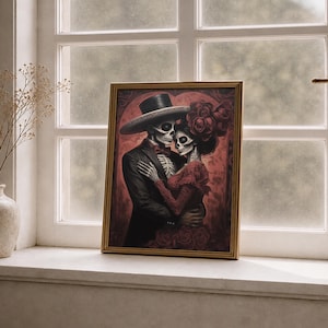 May include: A framed print showing a skeletal couple in an embrace. The male figure wears a black suit and hat, the female a red dress and roses. The artwork is themed around the Day of the Dead, with a dark red background.