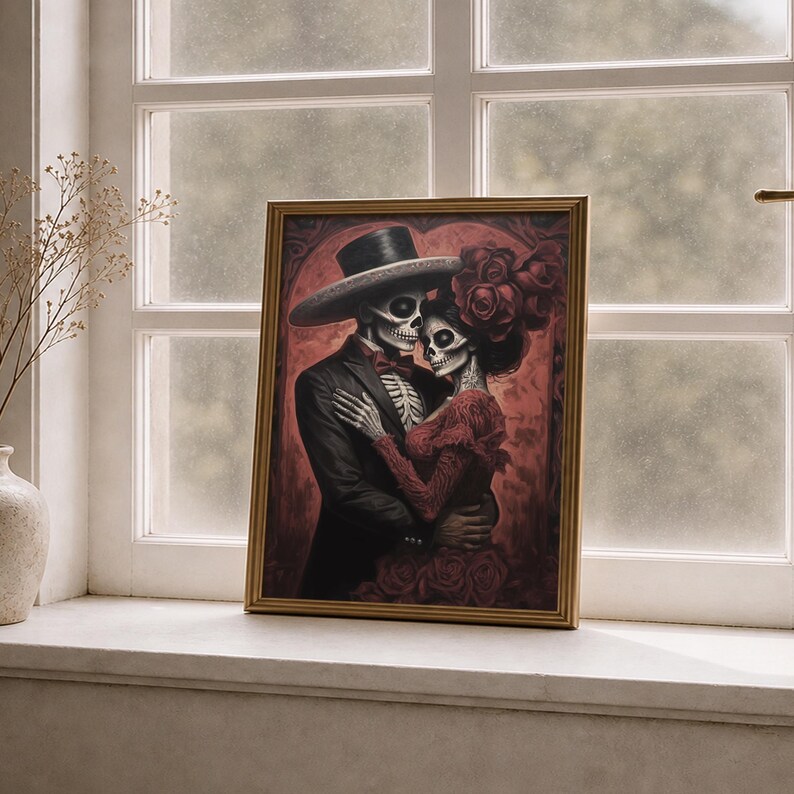 May include: A framed print showing a skeletal couple in an embrace. The male figure wears a black suit and hat, the female a red dress and roses. The artwork is themed around the Day of the Dead, with a dark red background.