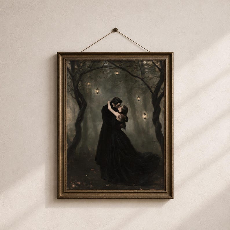 May include: A framed wall art print depicting two figures in long black clothing embracing in a dark, misty forest. The scene features twisted tree branches and several small, glowing lanterns suspended in the air, all enclosed in a dark frame.