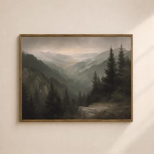 Könnte beinhalten: Gerahmtes Landschaftsgemälde, das ein nebliges Bergtal zeigt. Das Kunstwerk zeigt dunkelgrüne Bäume im Vordergrund und ein dunstiges, helles Tal in der Ferne. Das Gemälde befindet sich in einem goldfarbenen Rahmen.