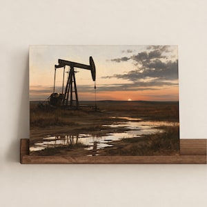 May include: A rectangular wall art print featuring a dark silhouette of an oil pump jack standing in a grassy field at sunset. The scene includes a muddy foreground with reflective puddles, a horizon line with a setting sun, and a cloudy sky.