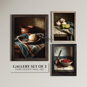 Puede incluir: Un conjunto de galería de tres impresiones artísticas de pared oscuras y enmarcadas. Las impresiones representan escenas de naturaleza muerta con una estética rústica, incluyendo pan, ajo, limas y chiles. Los marcos son marrón oscuro y negro.