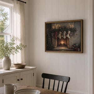 May include: A framed painting depicts a cozy Christmas scene. The artwork showcases a fireplace adorned with stockings, candles, and festive greenery. The painting is set in a room with a window, a cabinet, and a wooden table.