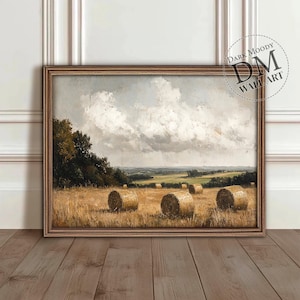 Op de afbeelding: Een ingelijst schilderij van een landelijk landschap met een veld vol hooibalen. De lucht is bewolkt en het veld is groen. Het schilderij is in een bruine lijst.