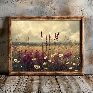 K&ouml;nnte beinhalten: Ein gerahmter Vintage-Druck eines Wildblumenfeldes. Die Blumen sind eine Mischung aus rosa und wei&szlig;, mit einem verschwommenen Hintergrund aus einem Feld und Himmel.