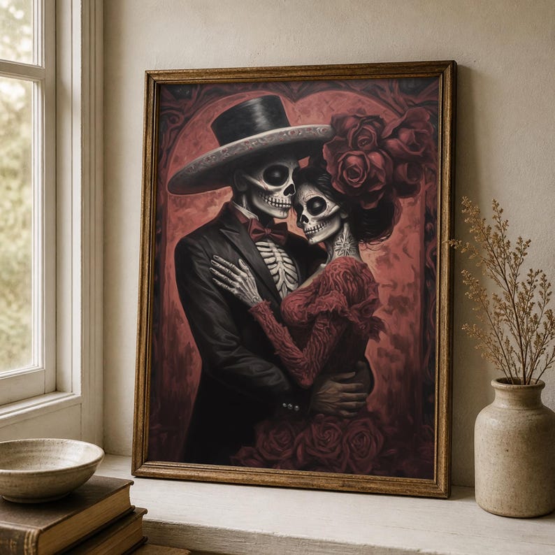 May include: A framed print showing a skeletal couple in an embrace, dressed in formal wear. The man wears a black suit and top hat, the woman a red dress and floral headpiece. The background is a deep red with an arched design.