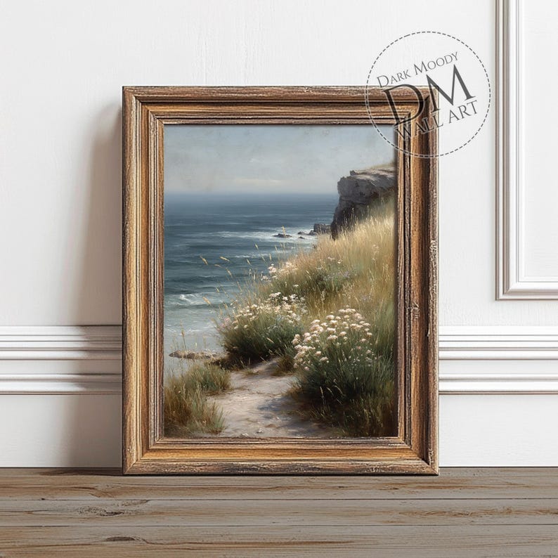 May include: A framed landscape print featuring a coastal scene. The artwork depicts a path leading to the ocean, with cliffs, tall grass, and white flowers. The frame is a warm, golden brown color. The text "DARK MOODY WALL ART" is visible.