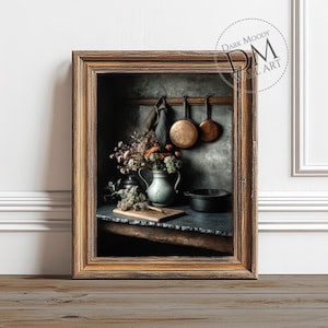 Pode incluir: Uma fotografia emoldurada de uma cena de cozinha rústica com uma panela de cobre pendurada em um gancho, um vaso de flores secas e uma panela de ferro fundido em uma bancada de madeira.