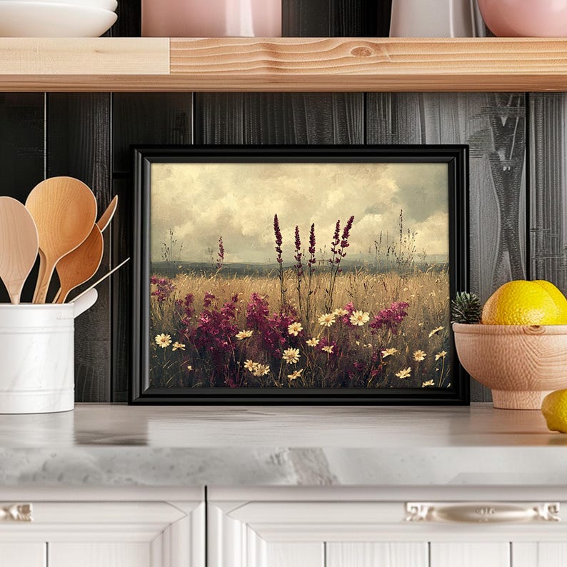 K&ouml;nnte beinhalten: Ein gerahmter Druck eines Feldes mit Wildblumen in weicher, vintage &Auml;sthetik. Die Blumen sind eine Mischung aus rosa und wei&szlig;, mit einem verschwommenen Hintergrund aus einem Feld und Himmel.