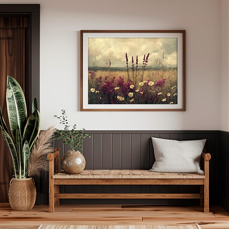 K&ouml;nnte beinhalten: Ein gerahmter Druck eines Feldes mit Wildblumen und einem bew&ouml;lkten Himmel im Hintergrund. Die Blumen sind in den Farben Rosa, Lila und Wei&szlig; gehalten.