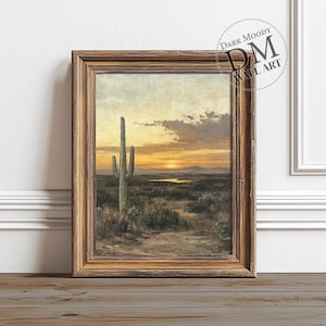 May include: A framed painting of a desert landscape with a tall cactus in the foreground. The sky is a warm orange and yellow, with a few clouds. The sun is setting in the distance, casting long shadows across the desert.
