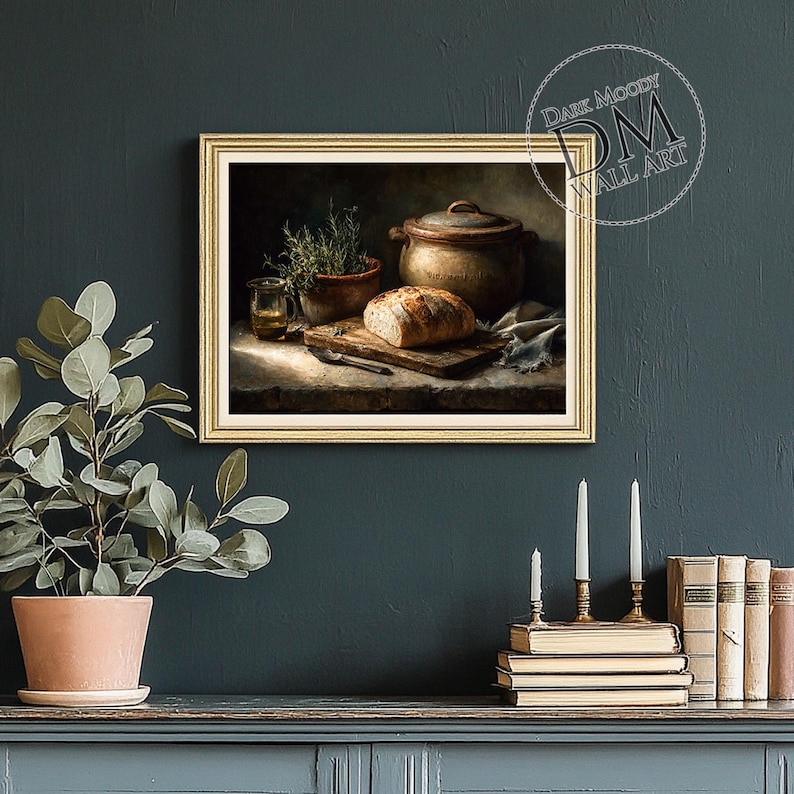 Op de afbeelding: Een ingelijste wandkunstprint toont een stilleven met een brood op een houten snijplank, een keramische pot en een kleine potplant. Het kunstwerk heeft een warm kleurenpalet en een rustieke esthetiek. De tekst "Dark Moody Wall Art" is zichtbaar.