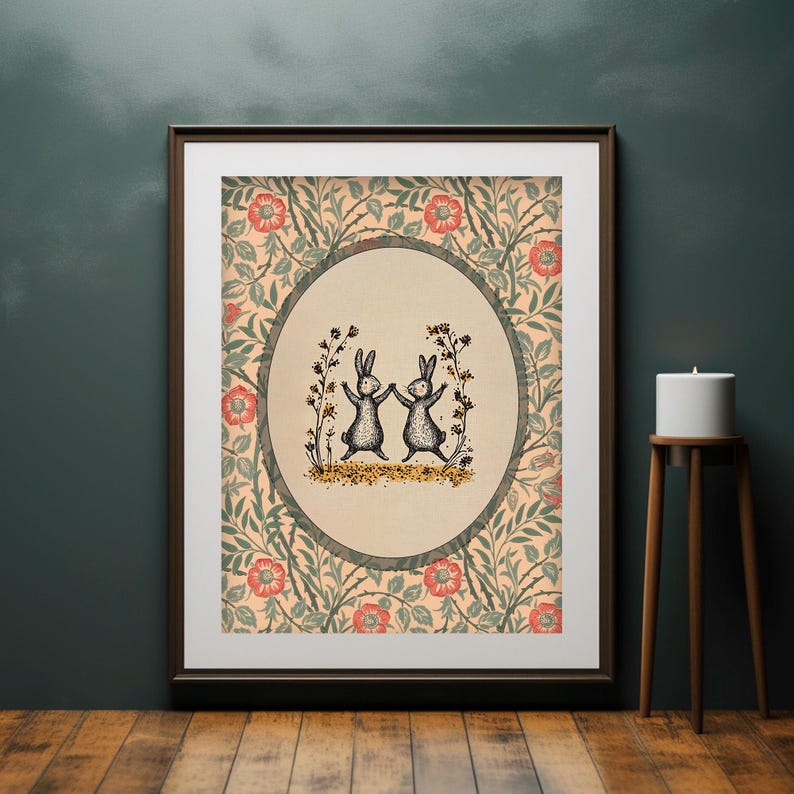 Pode incluir: Uma impress&atilde;o emoldurada com um padr&atilde;o floral vintage em tons de verde, rosa e creme. Dois coelhos pretos dan&ccedil;am em c&iacute;rculo dentro de um oval de cor creme. Os coelhos s&atilde;o cercados por pequenas flores amarelas.