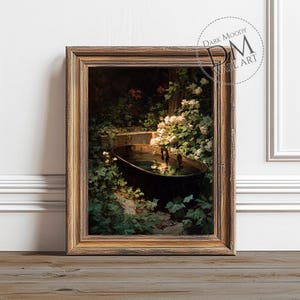 May include: A framed art print featuring a vintage painting of a black tub filled with water, surrounded by lush greenery and white flowers. The artwork is set in a garden scene, with a dark, moody aesthetic. The frame is a warm, antique gold color.