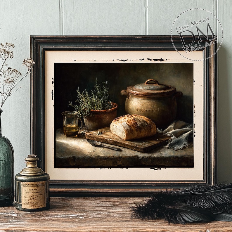 Op de afbeelding: Ingelijste kunstafdruk met een stilleven van een rustieke keuken. Een brood ligt op een houten plank naast een pot, een klein glaasje olie en een kruidenplant in pot. Het kunstwerk heeft een donkere, sfeervolle esthetiek.