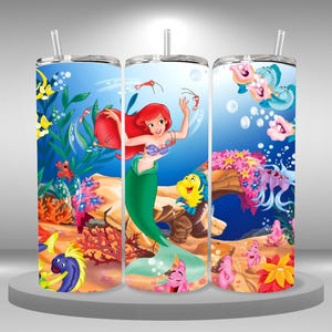 May include: Three stainless steel tumblers with a colorful design featuring Ariel, the Little Mermaid, swimming in the ocean with other sea creatures. The tumblers are decorated with bubbles, coral, and seaweed.