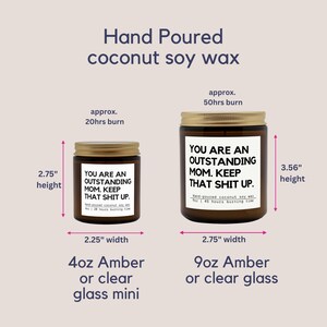 May include: Two amber glass candles with gold lids. The smaller candle is 7 cm tall and 5.7 cm wide, with a 20-hour burn time. The larger candle is 9 cm tall and 7 cm wide, with a 50-hour burn time. Both candles have the text "YOU ARE AN OUTSTANDING MOM. KEEP THAT SHIT UP."