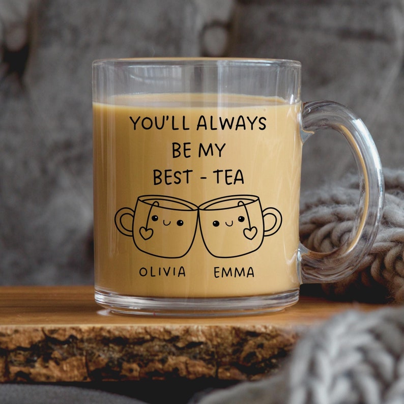 A clear mug with a black design and text with light brown liquid in it