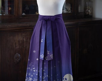 May include: A purple skirt with a high waist and a bow. The skirt features a gradient design, transitioning from a deep purple to a lighter shade with white floral and skull patterns. The skirt is displayed on a mannequin.