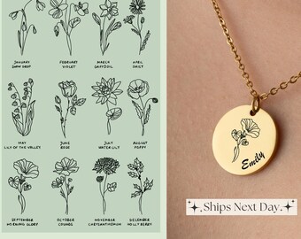 May include: A gold necklace with a round pendant featuring a delicate floral design and the name "Emily" engraved on it. The pendant is surrounded by a thin gold chain. The necklace is displayed against a light green background with a chart of flowers representing each month of the year.