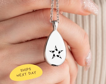 May include: A silver-colored teardrop pendant necklace with a black star design composed of musical notes. The pendant hangs from a delicate chain. The image also includes a yellow sticker with the text "SHIPS NEXT DAY".
