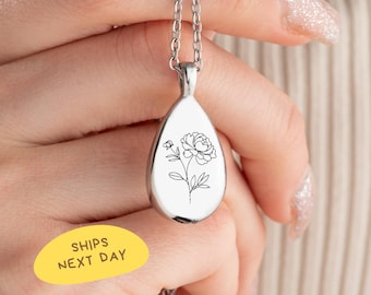 May include: Silver-toned teardrop pendant necklace with a delicate black floral design. The pendant hangs from a fine chain. The image includes the text "SHIPS NEXT DAY" on a yellow oval.
