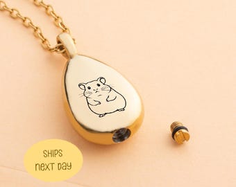May include: A gold-colored teardrop-shaped pendant necklace with a chain. The pendant features a black line drawing of a hamster. A small screw is next to the pendant. The text "SHIPS next day" is on a yellow oval.