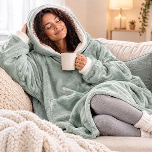 Puede incluir: Una sudadera con capucha de gran tama&ntilde;o en color verde salvia con forro de vell&oacute;n sherpa blanco, mangas largas con pu&ntilde;os acanalados y un bolsillo frontal grande. La prenda est&aacute; hecha de una tela suave y afelpada con una capucha.