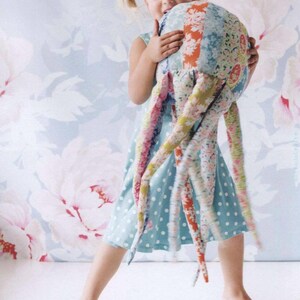 May include: A plush octopus toy constructed from various floral and patterned fabric patches in shades of blue, pink, orange, and green. The stuffed creature features a rounded head and multiple long, dangling tentacles made of assorted textiles.