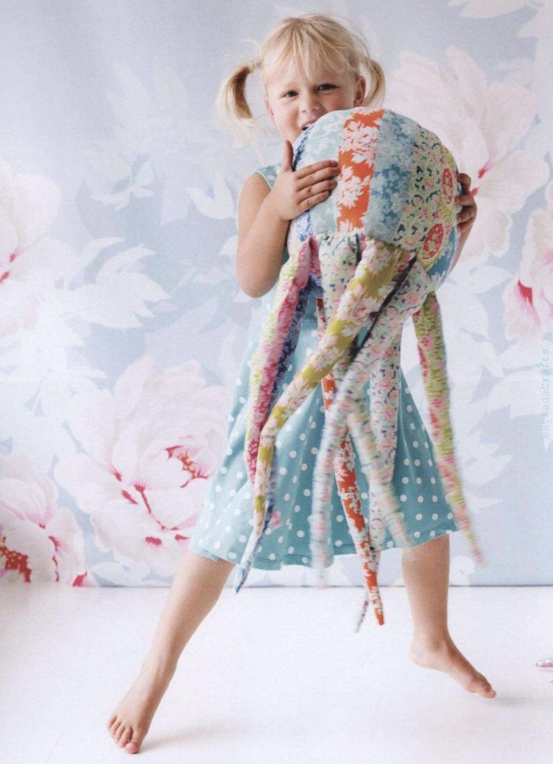 May include: A plush octopus toy constructed from various floral and patterned fabric patches in shades of blue, pink, orange, and green. The stuffed creature features a rounded head and multiple long, dangling tentacles made of assorted textiles.
