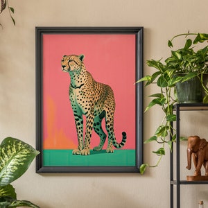 K&ouml;nnte beinhalten: Ein gerahmter Druck eines Geparden, der auf einem gr&uuml;nen Hintergrund steht. Der Gepard blickt nach rechts und hat einen rosa Hintergrund hinter sich.