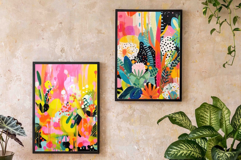 May include: Two framed abstract paintings with colourful floral and geometric designs. The paintings are in black frames and are hanging on a light beige wall.