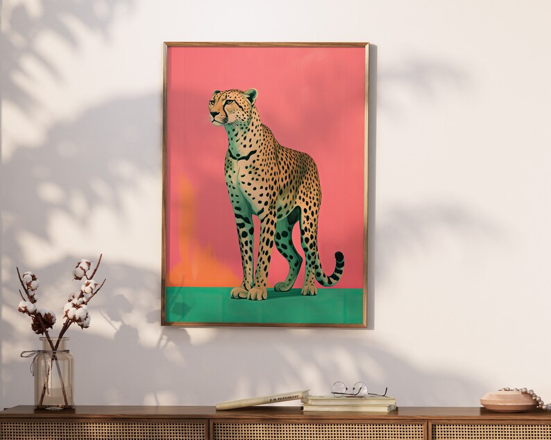 K&ouml;nnte beinhalten: Ein gerahmter Druck eines Geparden, der auf einem gr&uuml;nen Hintergrund mit einem rosa Hintergrund dahinter steht. Der Gepard blickt nach rechts und hat ein geflecktes Fell.