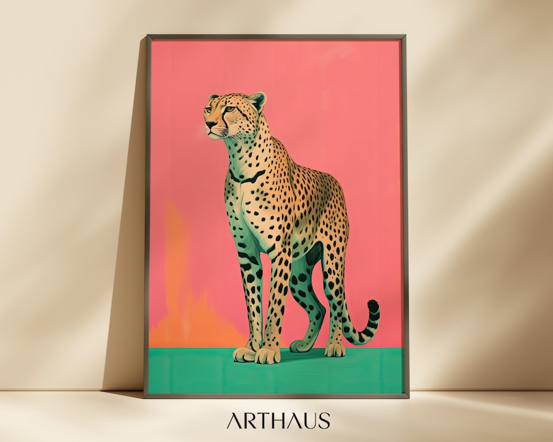 K&ouml;nnte beinhalten: Ein Gepard mit geflecktem Fell steht auf einer gr&uuml;nen Fl&auml;che vor einem rosafarbenen Hintergrund. Der Gepard schaut nach links aus dem Bild. Das Bild ist mit einem schwarzen Rahmen gerahmt und das Wort "ARTHAUS" ist unter dem Rahmen gedruckt.