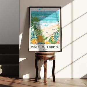 May include: A framed poster featuring a colourful illustration of a beach scene in Playa del Carmen, Mexico. The poster depicts a view of the ocean, beach, and palm trees. The text "PLAYA DEL CARMEN" and "MEXICO" is printed below the illustration.