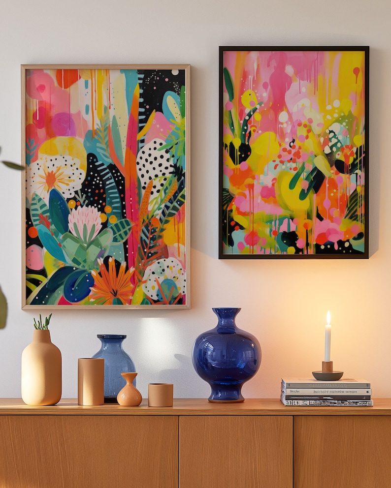 May include: Two framed abstract paintings with bright colours and bold brushstrokes, a blue ceramic vase, three smaller vases, and two books on a wooden shelf.