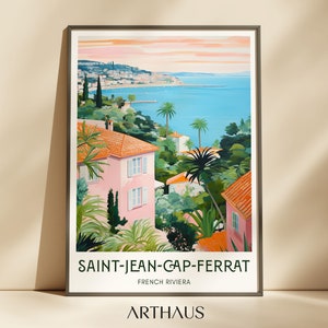 May include: A colourful illustration of a seaside town with pink buildings, palm trees, and a view of the ocean. The text "SAINT-JEAN-CAP-FERRAT" and "FRENCH RIVIERA" is printed below the image.