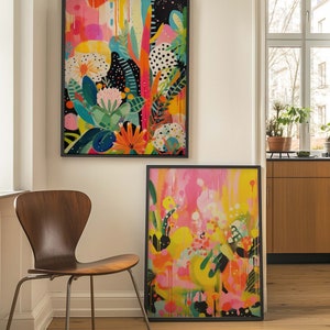 May include: Two framed abstract paintings with bright colours and bold patterns. The paintings feature a mix of pink, yellow, green, and black. The paintings are hung on a white wall.