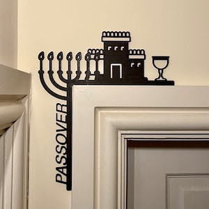 May include: Black metal Passover decor featuring a menorah, a house, and a cup. The word "PASSOVER" is written vertically on the side.