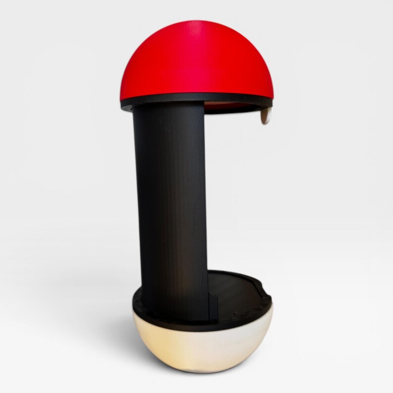 Puede incluir: Un soporte vertical con una c&uacute;pula superior roja, un pilar central negro y una base redondeada blanca. La estructura tiene un dise&ntilde;o abierto con una secci&oacute;n superior roja curva y una base blanca a juego, conectadas por un soporte vertical negro s&oacute;lido.