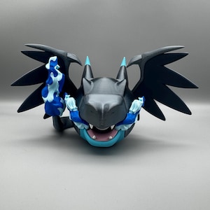 May include: A 3D-printed dragon figure in grey, black, and blue. The dragon has large wings, a detailed head, and blue flames. The figurine is a stylized representation of a fantasy creature.