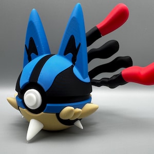 May include: A 3D-printed Lucario figure in blue, black, tan, and red. The figure has a blue head with black details, tan spikes, and red and black appendages. A white circular detail is on the front of the figure.