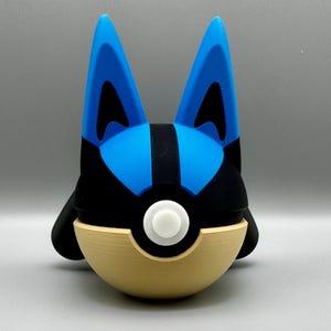 May include: A 3D-printed Lucario figure, featuring a blue and black head with large, pointed ears. The figure is set atop a tan and white Poké Ball base, creating a unique fusion of character and design.