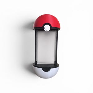 Puede incluir: Una vitrina vertical con una mitad superior roja y una mitad inferior blanca, que recuerda al dise&ntilde;o de una esfera. La secci&oacute;n central es una ventana rectangular transparente con marco negro y un peque&ntilde;o bot&oacute;n circular de color blanco.