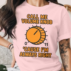 May include: Light pink t-shirt with the text "CALL ME VOLUME KNOB 'CAUSE I'M ALWAYS RIGHT" in orange and black. The design includes an orange volume knob graphic with the numbers 0 and 11.