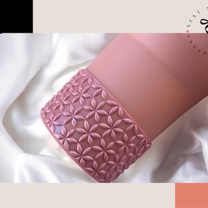 a pink vase sitting on top of a white sheet