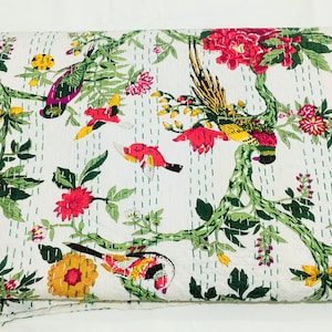 May include: White quilt with a vibrant floral and bird design. The quilt features colorful birds, red and pink flowers, and green foliage. The design is printed on a white background with green stitching.